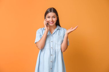 Arka planda cep telefonuyla konuşan genç bir kadın.