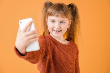 Küçük kız renk geçmişinde selfie çekiyor.