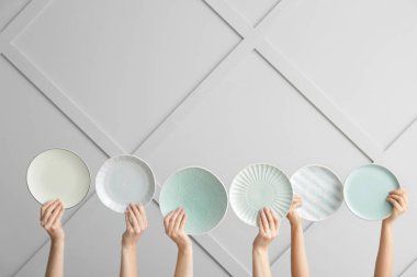 Açık arkaplanda farklı temiz tabaklar olan eller