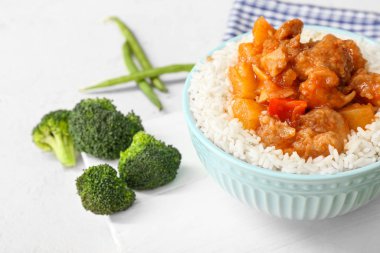 Lezzetli pirinçli kase, tavuk ve sebzeler beyaz masada.