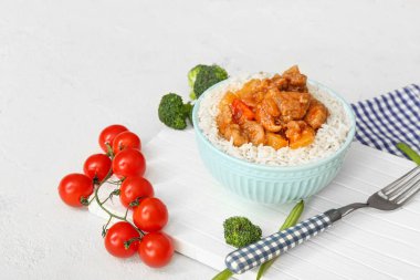 Lezzetli pirinçli kase, tavuk ve sebzeler beyaz masada.