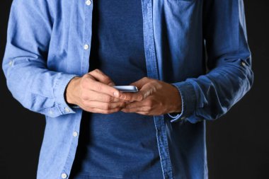 Modaya uygun mavi elbiseli ve cep telefonlu bir adam, yakın plan.