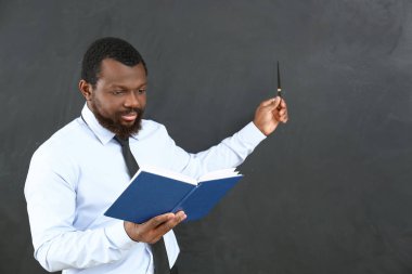 Sınıftaki tahtaya işaret eden Afro-Amerikan öğretmen.