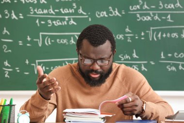 Hoşnutsuz Afro-Amerikan öğretmen sınıfta ödevlerini kontrol ediyor.