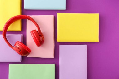 Kitap ve renk arka plan üzerinde modern kulaklıklar. Audiobook kavramı