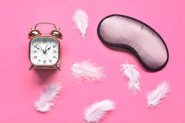 Sleep mask with alarm clock and feathers on color background — 스톡 사진