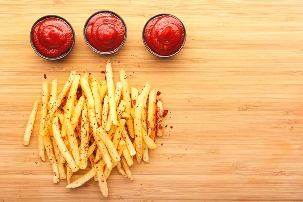 Velsmagende pommes frites og tomatsauce på træbaggrund - Stock-foto