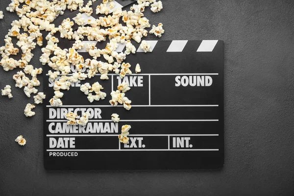 Smaczny popcorn z klaskaczem filmowym na ciemnym tle — Zdjęcie stockowe