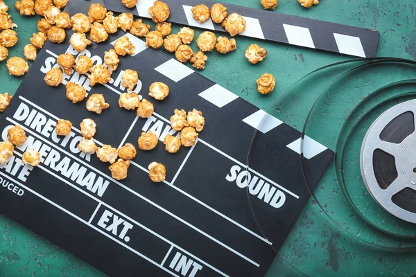Smaczny popcorn z klaskaczem filmowym i filmem na kolorowym tle — Zdjęcie stockowe