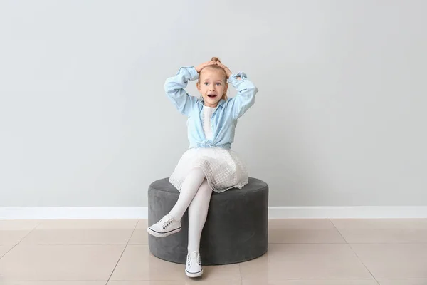 Roztomilé holčička v podzimním oblečení sedí v blízkosti šedé zdi — Stock fotografie