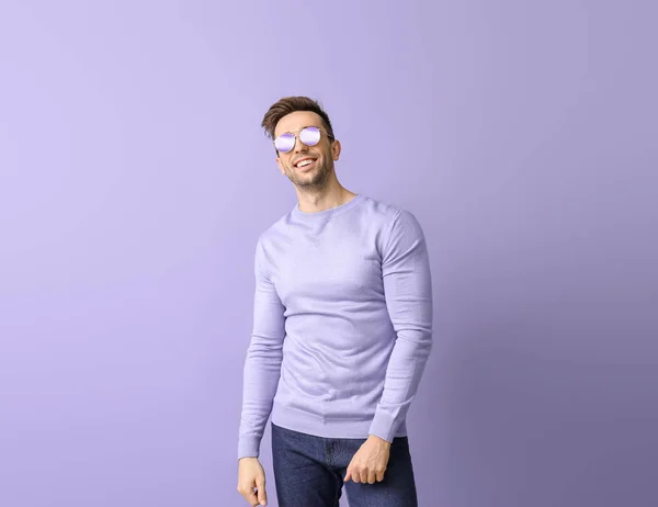 Hombre joven con gafas de sol con estilo en el fondo de color — Foto de Stock
