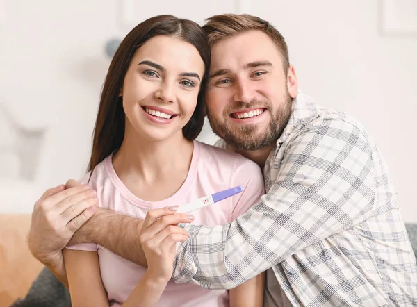 Šťastný mladý pár s těhotenským testem doma — Stock fotografie