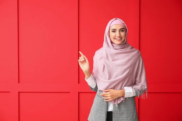 Schöne arabische Frau zeigt auf etwas auf farbigem Hintergrund — Stockfoto