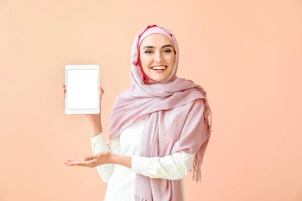 Beautiful Arab woman with tablet computer on color background — ストック写真