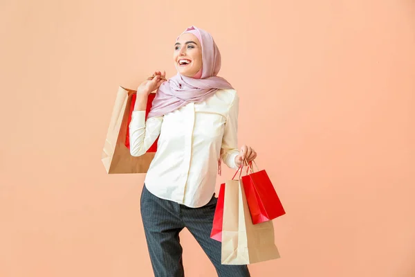 Mulher árabe bonita com sacos de compras no fundo de cor — Fotografia de Stock