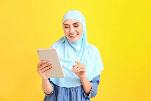 Beautiful Arab woman with tablet computer on color background — ストック写真