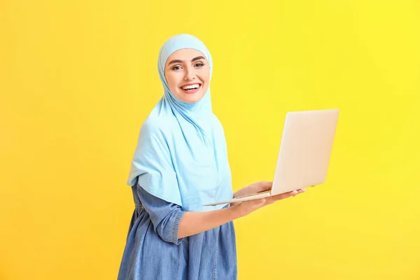 Mujer árabe hermosa con el ordenador portátil en el fondo de color —  Fotos de Stock