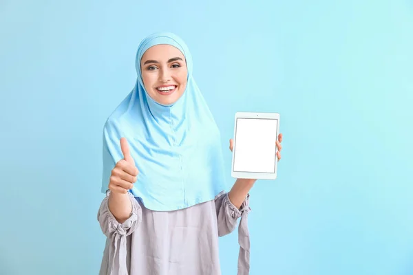 Hermosa mujer árabe con tableta que muestra el pulgar hacia arriba en el fondo de color —  Fotos de Stock