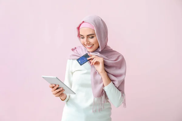 Mujer árabe hermosa con tableta y tarjeta de crédito en el fondo de color —  Fotos de Stock