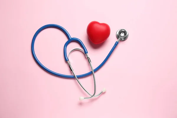 Modern stethoscope and red heart on color background — Stock Photo, Image