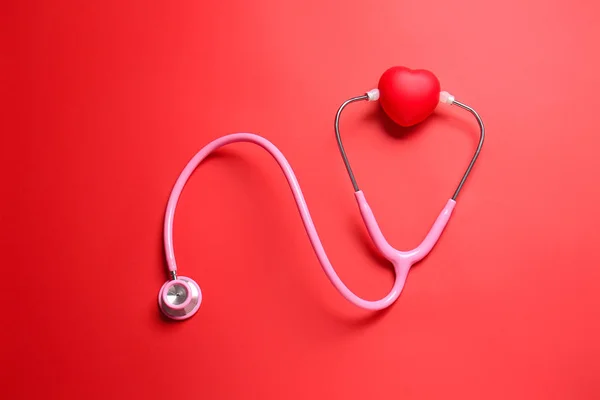 Modern stethoscope and red heart on color background — Stock Photo, Image