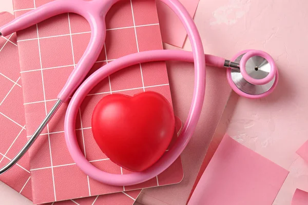 Stethoscope, notebooks and heart on color background — ストック写真