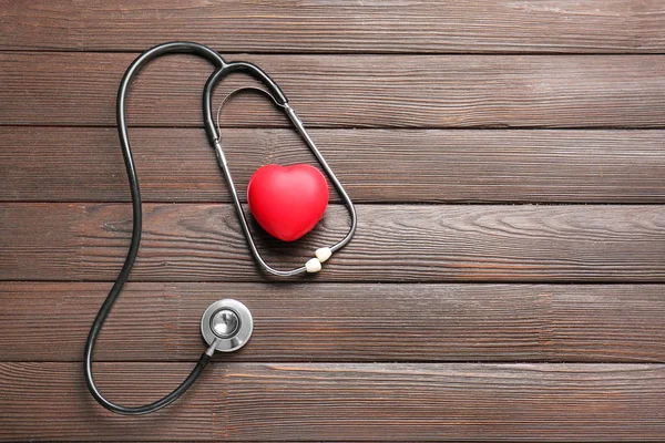 Stethoskop und Herz auf Holzgrund — Stockfoto