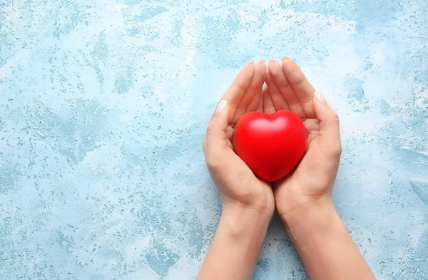 Mani femminili con cuore su sfondo a colori — Foto Stock