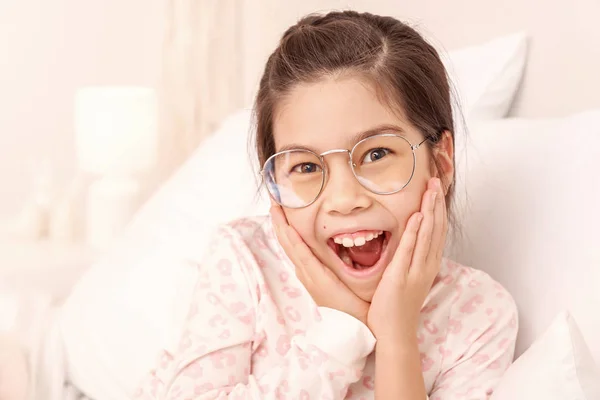 Bonito menina surpreso com óculos na cama — Fotografia de Stock