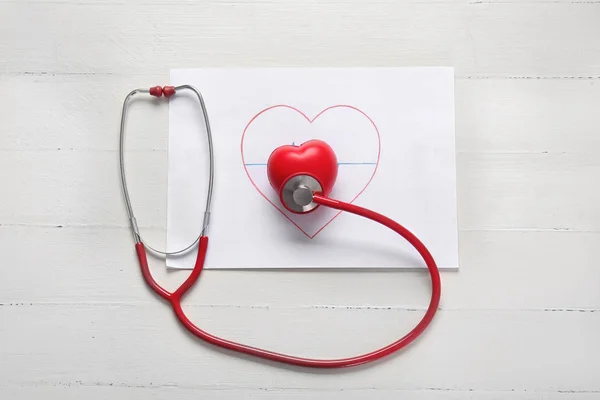 Drawing, heart and stethoscope on white table — Stock Photo, Image