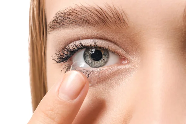 Mladá žena uvedení kontaktní čočky na bílém pozadí, detailní záběr — Stock fotografie
