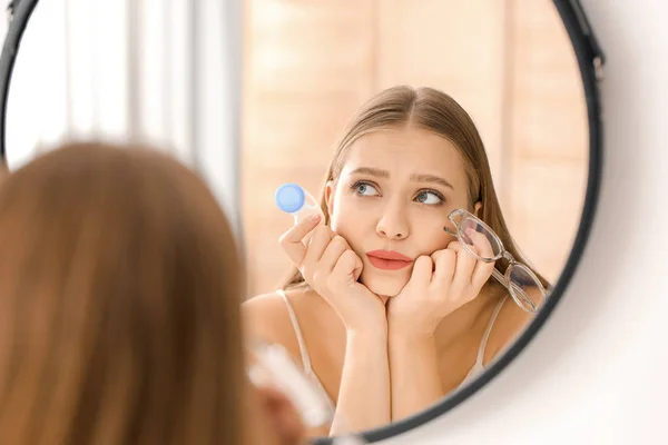 Mujer reflexiva con estuche de lentes de contacto y anteojos cerca del espejo — Foto de Stock