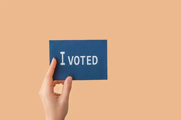 Hand holding paper with text I VOTED on color background — Stock Photo, Image