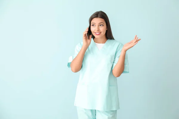 年轻的护士用彩色背景的手机交谈 — 图库照片