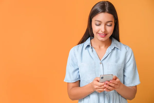 Young woman with mobile phone on color background — Stock Photo, Image