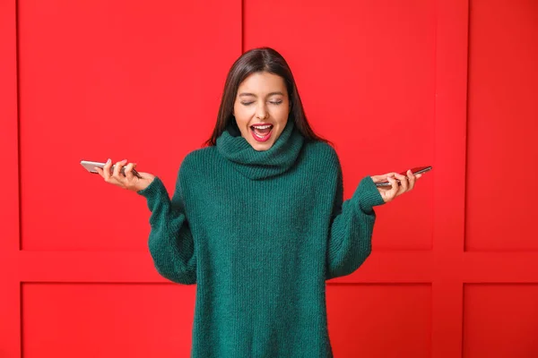 Young woman with mobile phones on color background — Stock Photo, Image