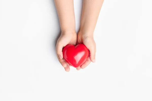 Manos de niño con corazón rojo sobre fondo blanco. Concepto de cardiología — Foto de Stock