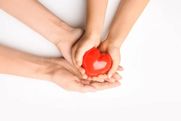 Mani di bambino e adulto con cuore rosso su sfondo bianco. Concetto di cardiologia — Foto Stock