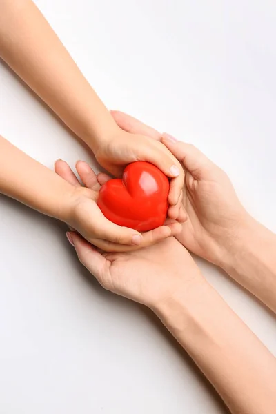 Gyermek és felnőtt kezek piros szívvel, fehér háttérrel. Kardiológiai fogalom — Stock Fotó