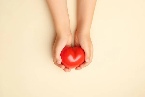 Ręce dziecka z czerwonym sercem na tle koloru. Koncepcja kardiologii — Zdjęcie stockowe