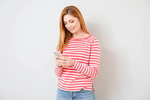 Mujer joven con teléfono móvil sobre fondo claro — Foto de Stock