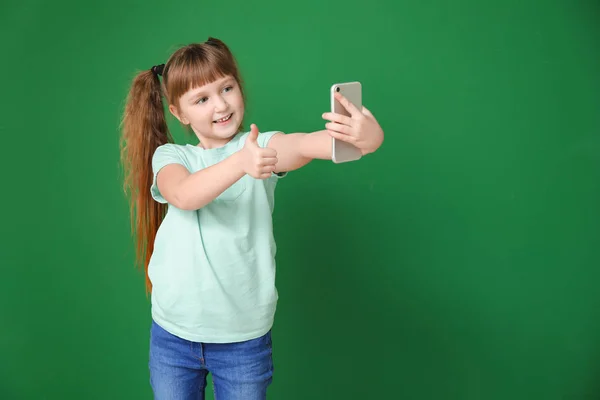 Little girl taking selfie on color background — ストック写真