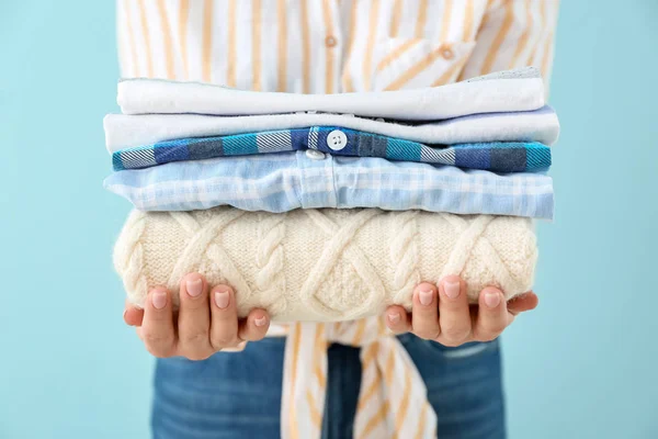 Young woman with clean laundry on color background, closeup — Stock Photo, Image