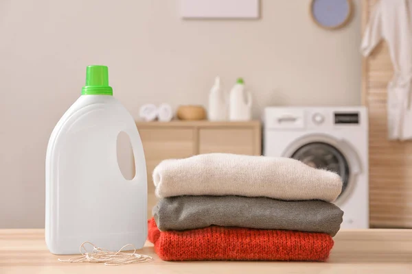 Clean laundry and washing liquid on table in bathroom