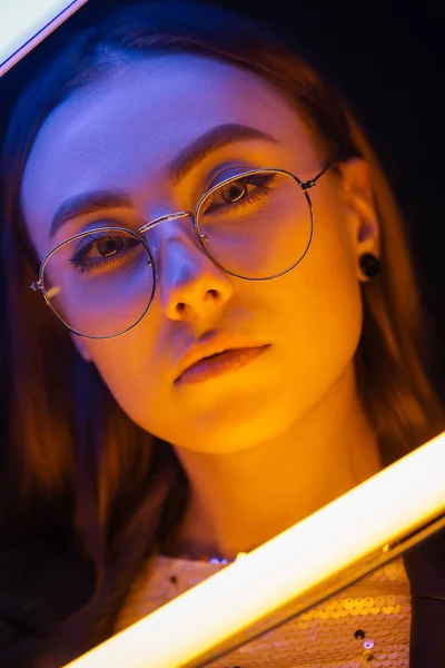 Toned portrait of beautiful woman with neon lamps on dark background — Stock Photo, Image