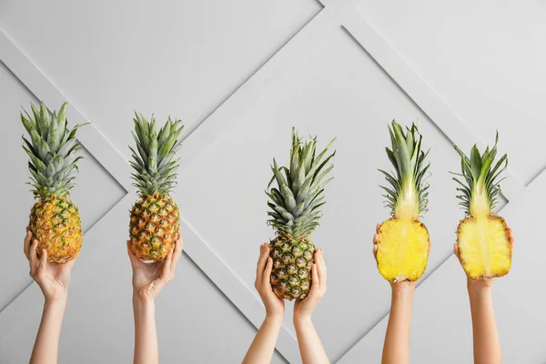 Hands with juicy pineapples on light background — Stock Photo, Image