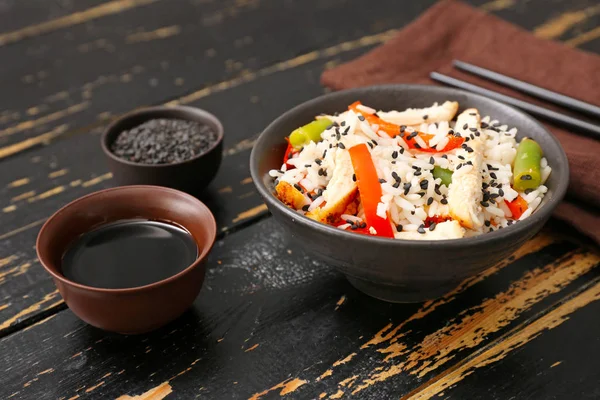 Bowl with tasty rice, chicken and vegetables on dark wooden background — Stock Photo, Image