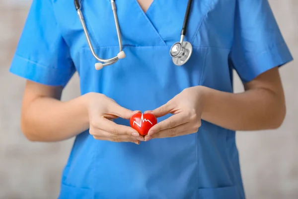 Женщина-кардиолог с красным сердцем на светлом фоне — стоковое фото