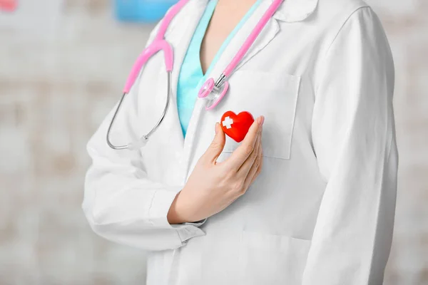 Female cardiologist with red heart on light background — Stock Photo, Image