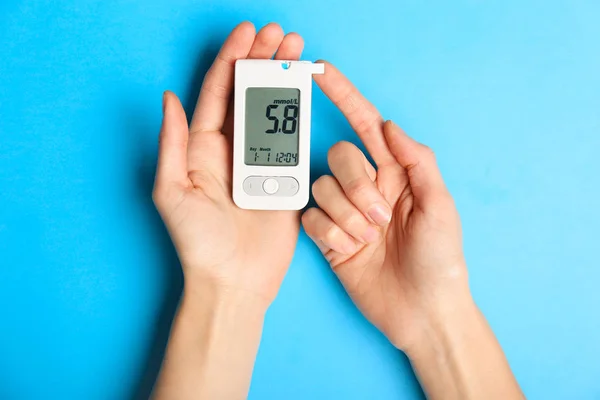 Hands of diabetic woman with digital glucometer on color background — 스톡 사진